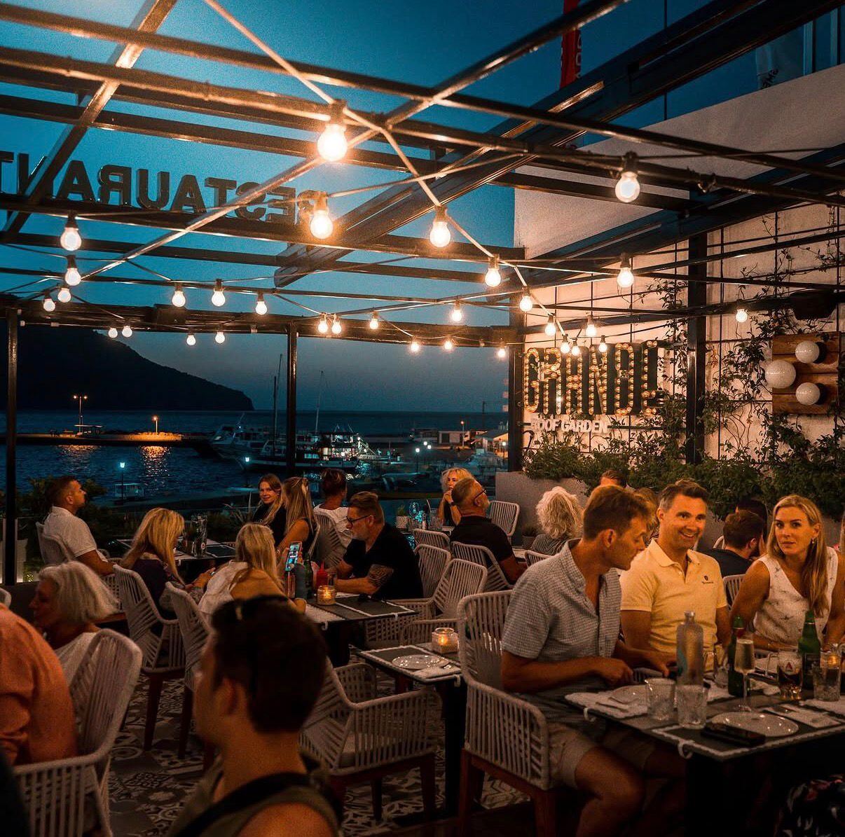 Evening dining under festoon lights at Grande rooftop restaurant, Karpathos